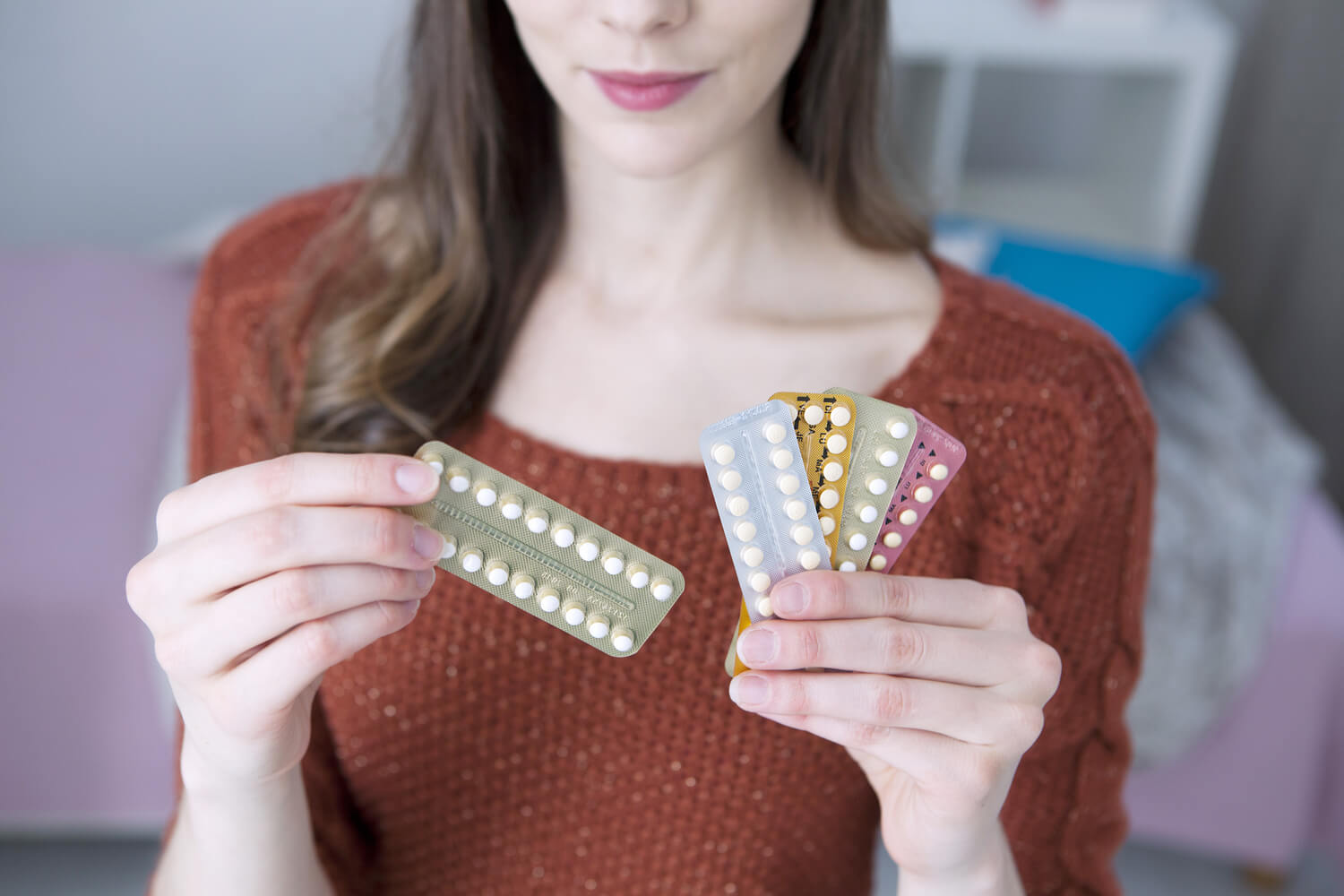 Woman holding different brands of birth control pills