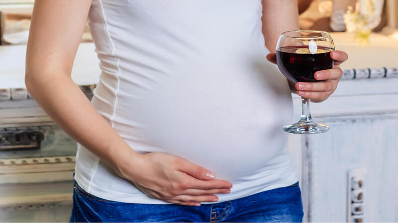 pregnant woman holdingm a glass of red wine