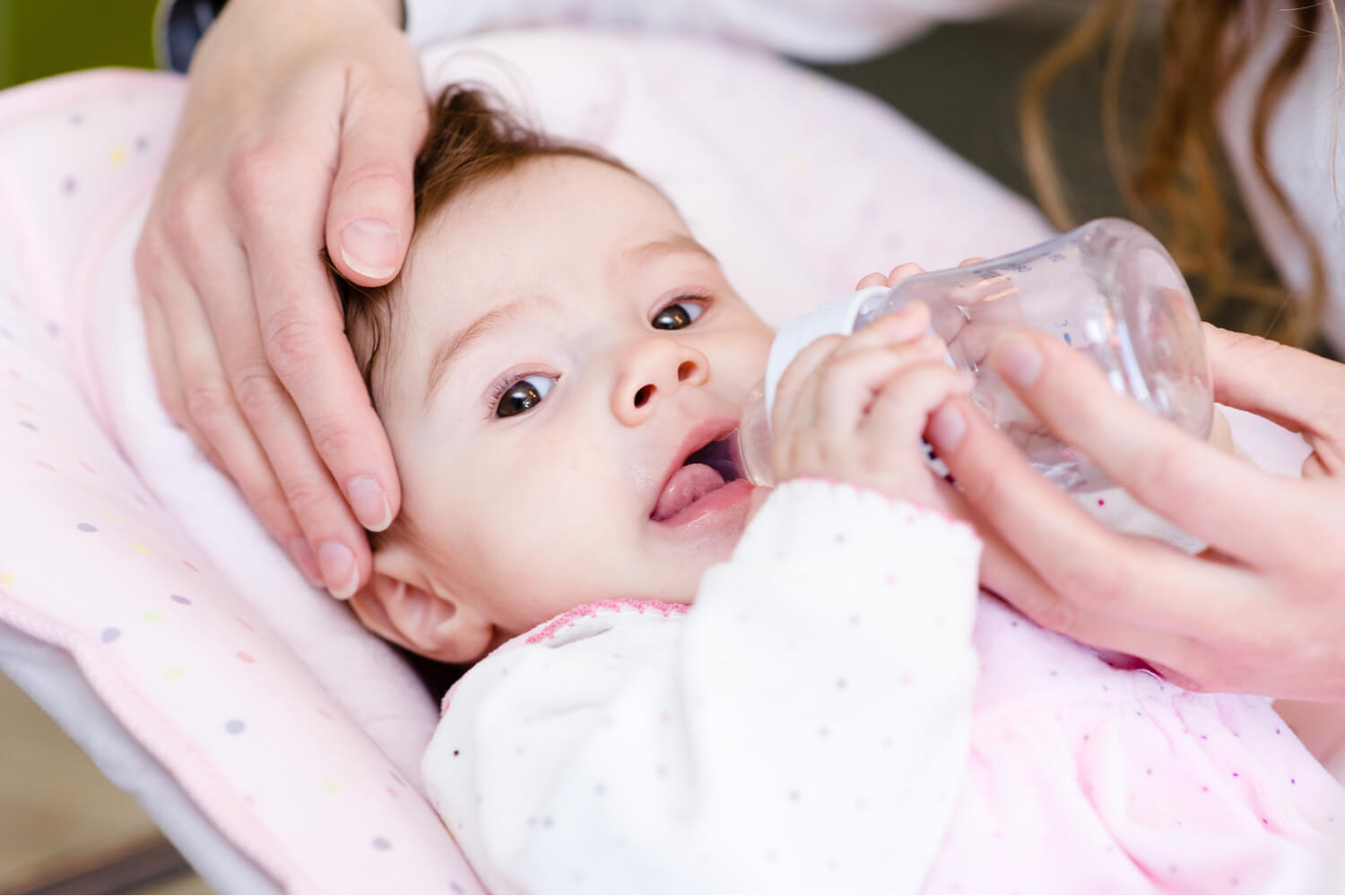 mom feeding water to baby in bottle