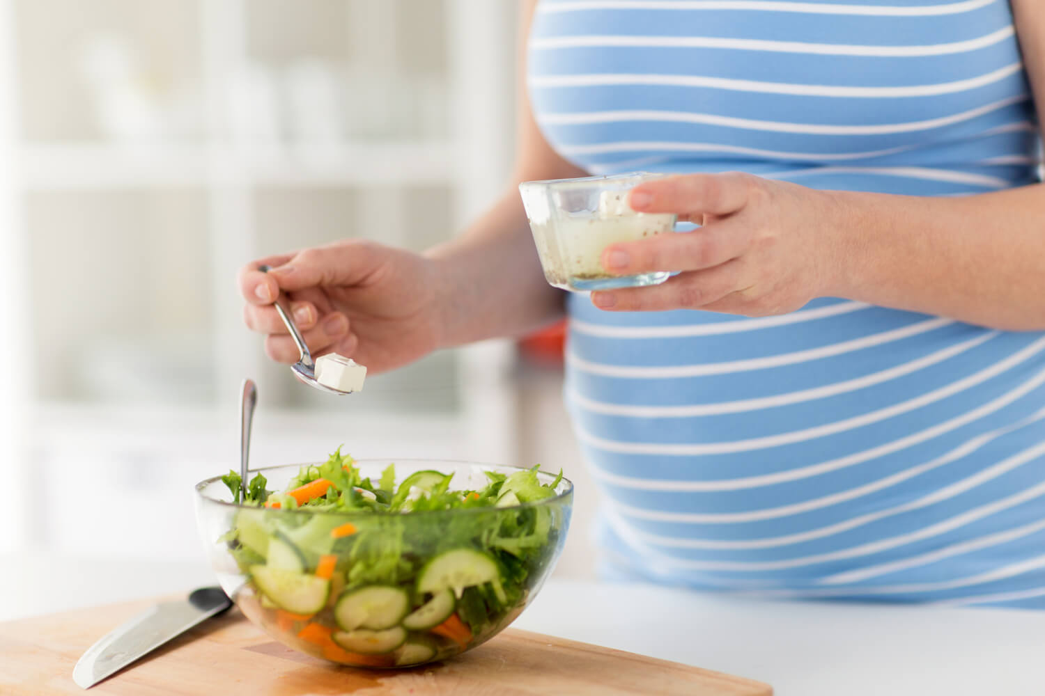 pregnant women preparing salad with feta cheese