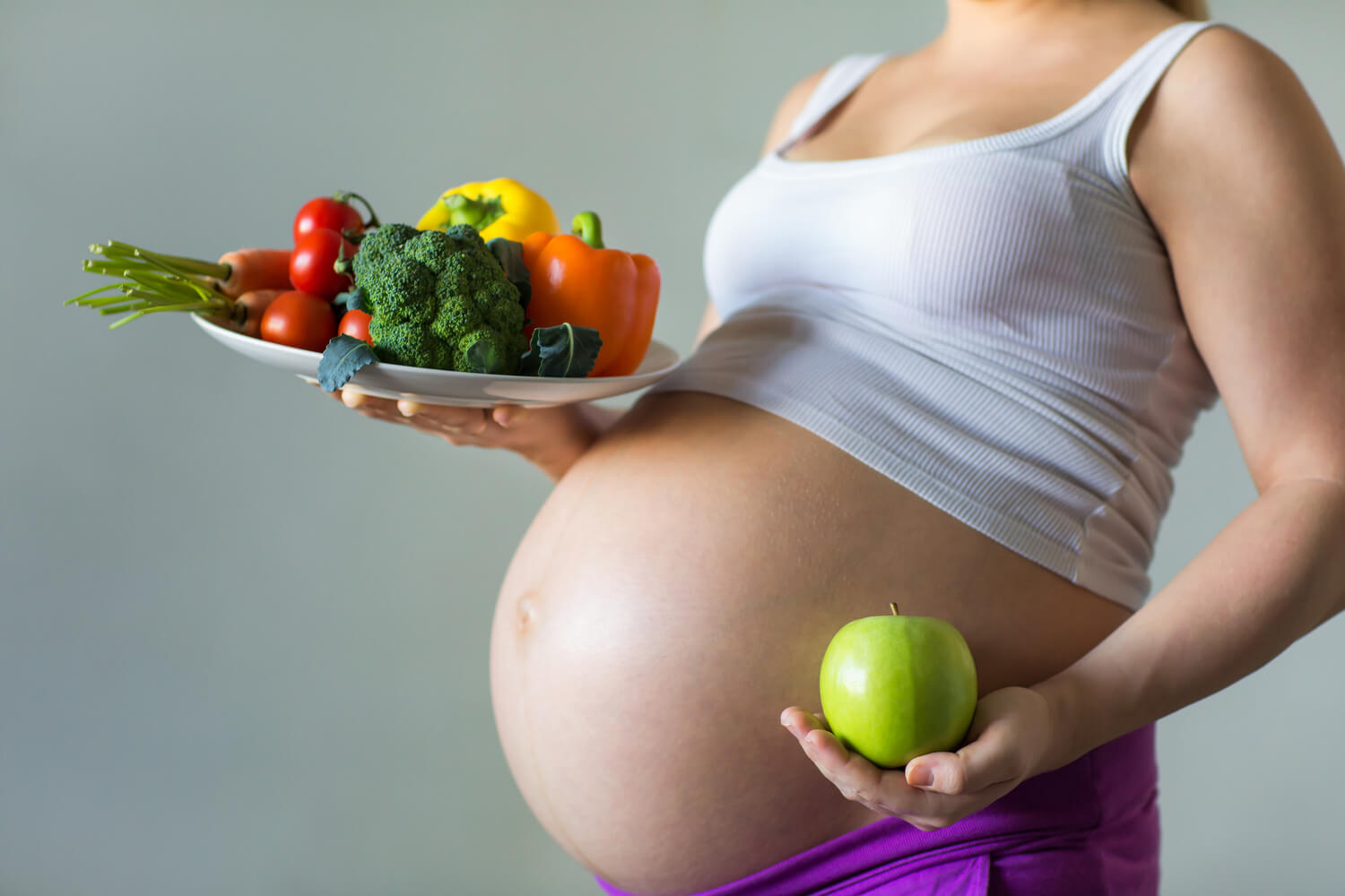 pregnant women hold plate of veggies