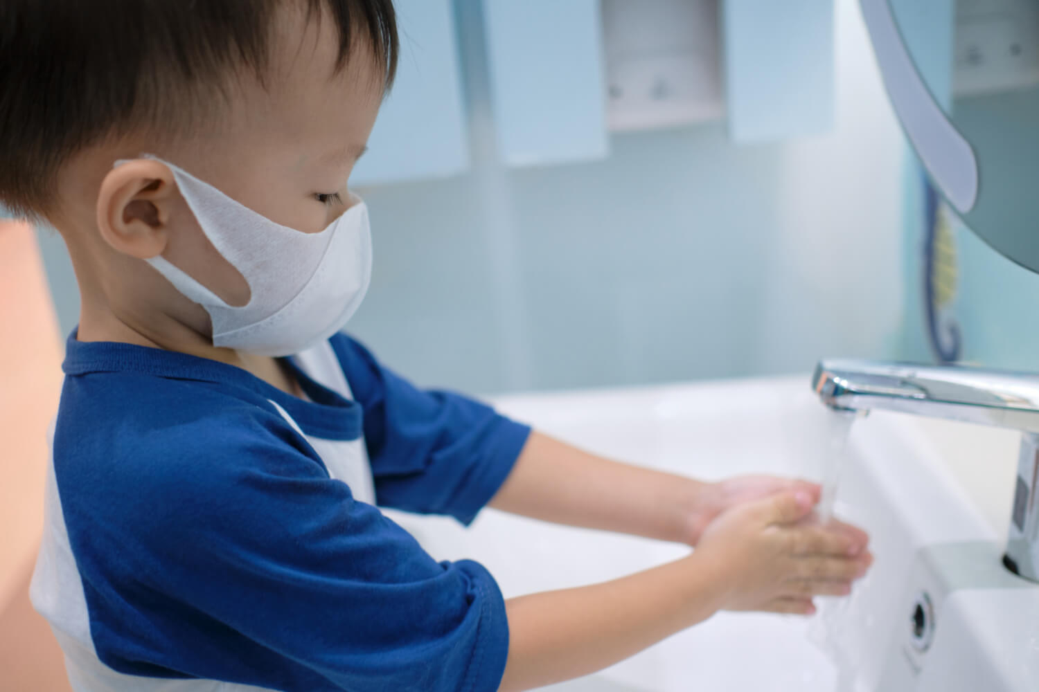 toddler in mask washing hands
