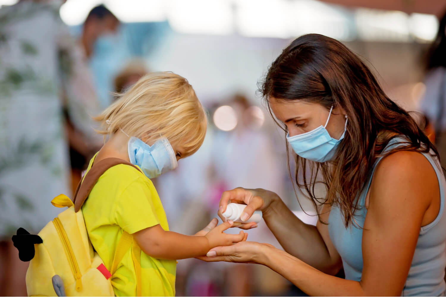 mom using hand sanitizer on her toddler son's hand