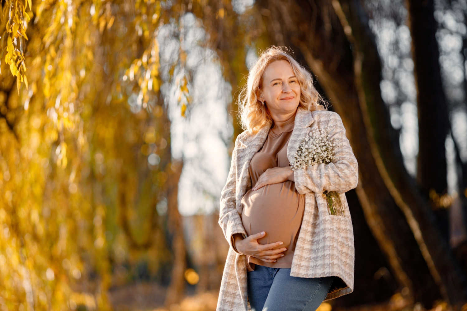 happy and positive pregnant woman standing with her hands on belly