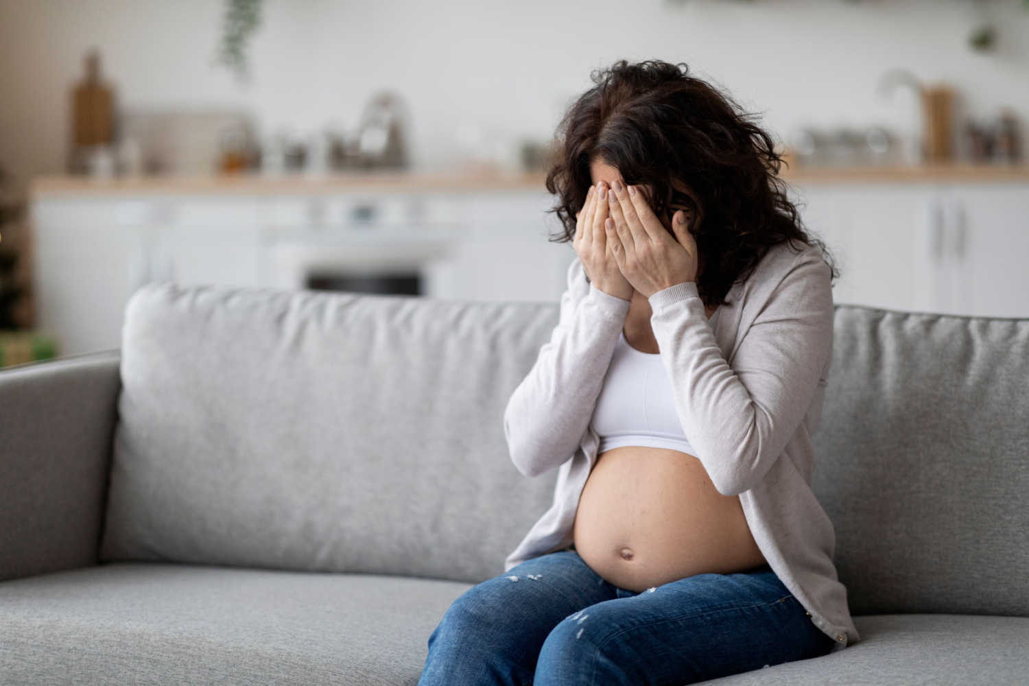 sad pregnant woman covering her face 