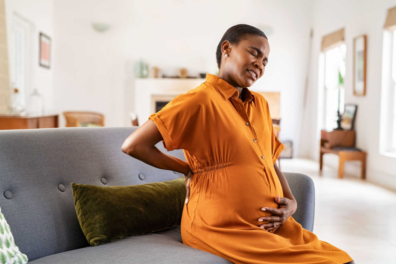 uncomfortable pregnant woman holding belly and back