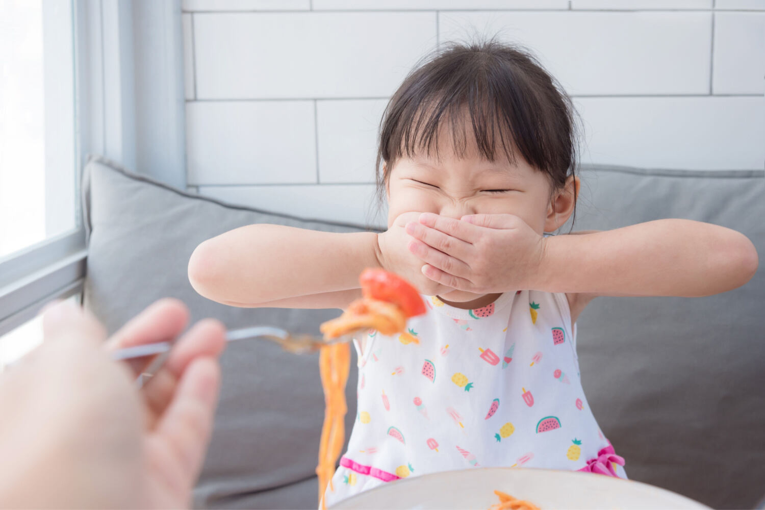 A toddle girl closing her mouth to avoid eating