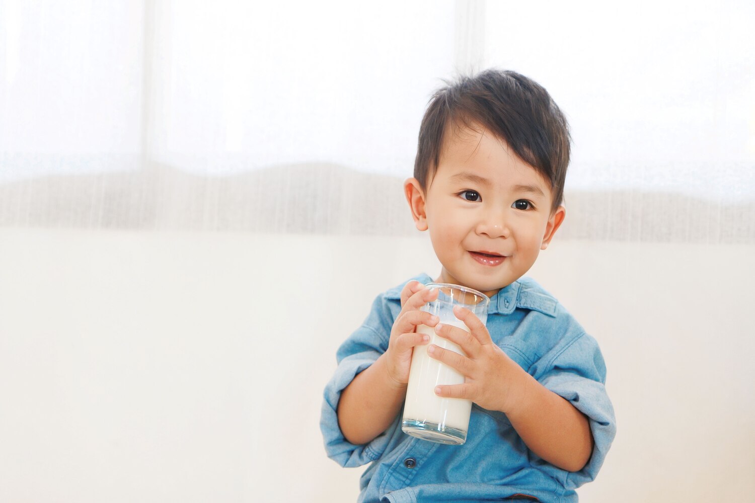 A toddler with a glass of milk
