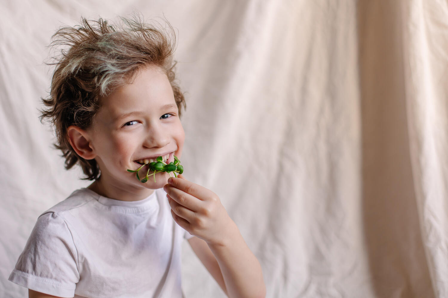 A boy eating green vegetables