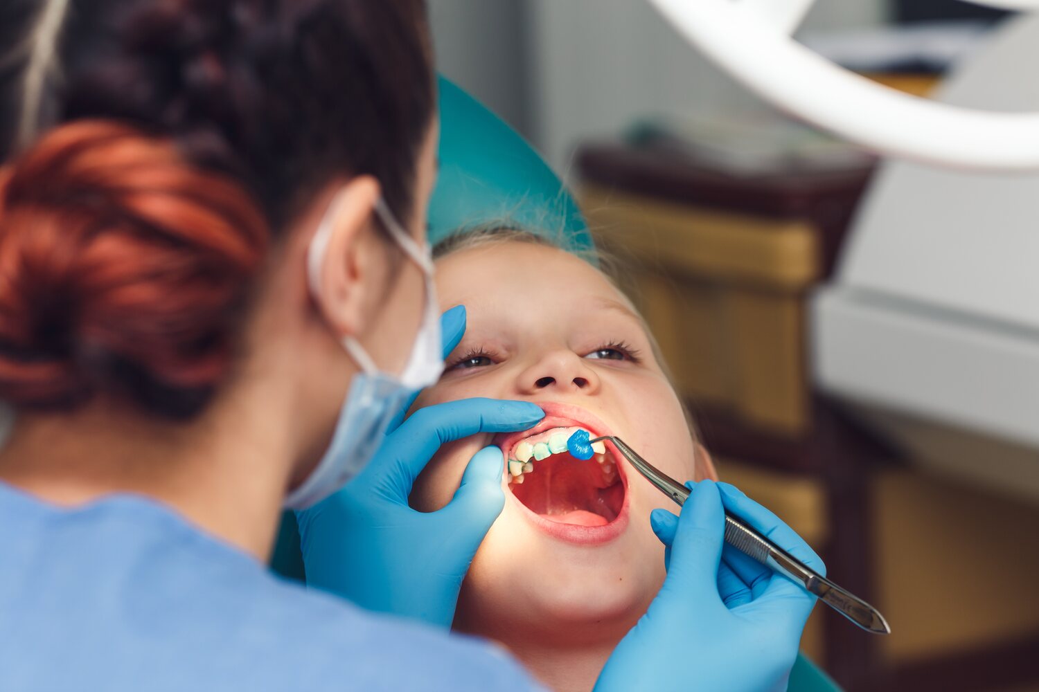 A dentist doing fluoride treatment on a kid's teeth