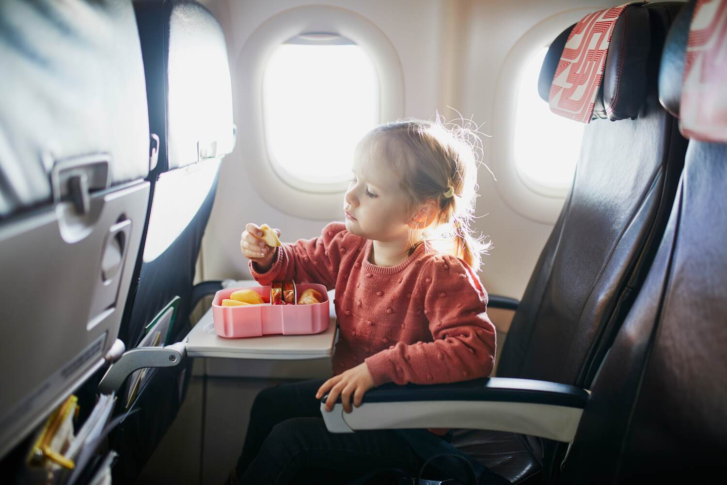 A toddler eating fruits on a flight