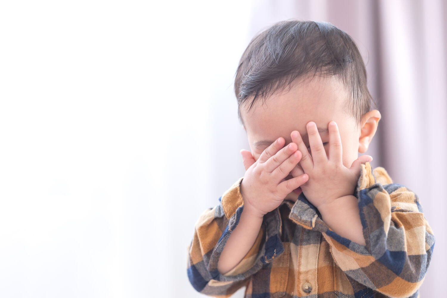 A toddler playing hide and seek