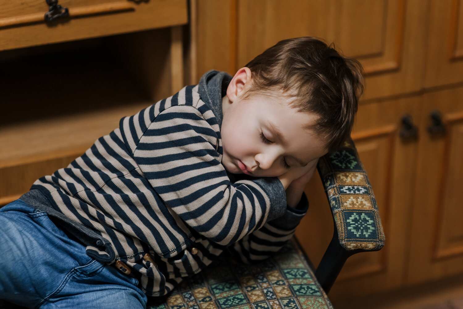 A tired toddler sleeping on chair