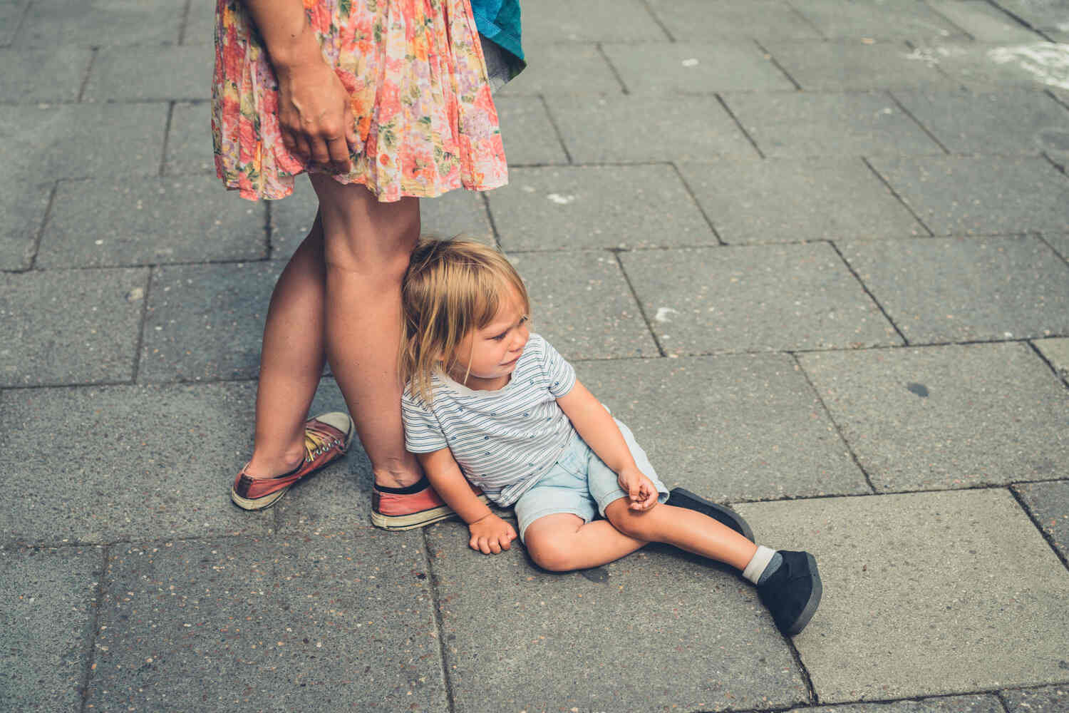 A toddler sitting on street and crying
