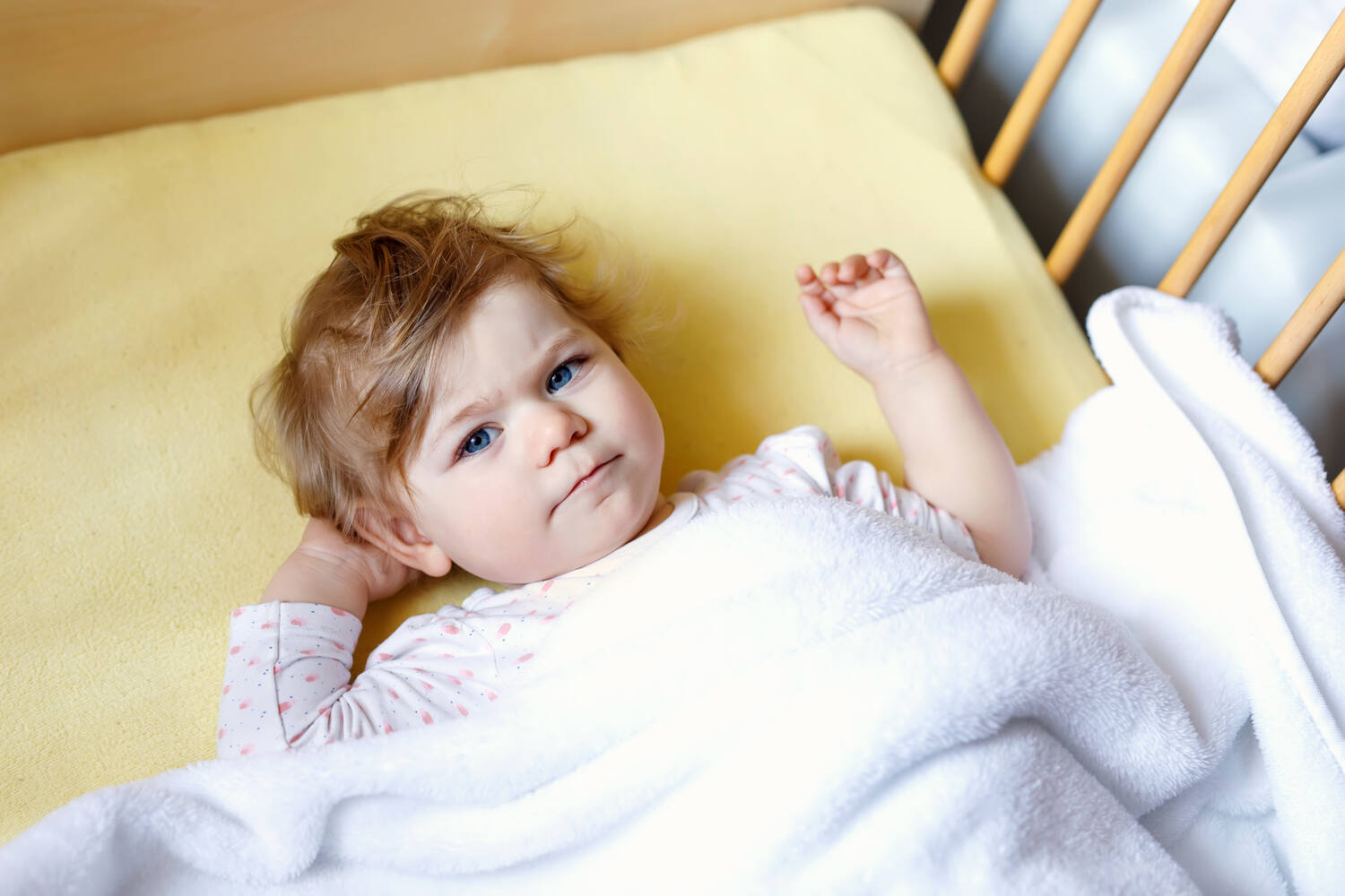 A toddler girl lying awake in cot