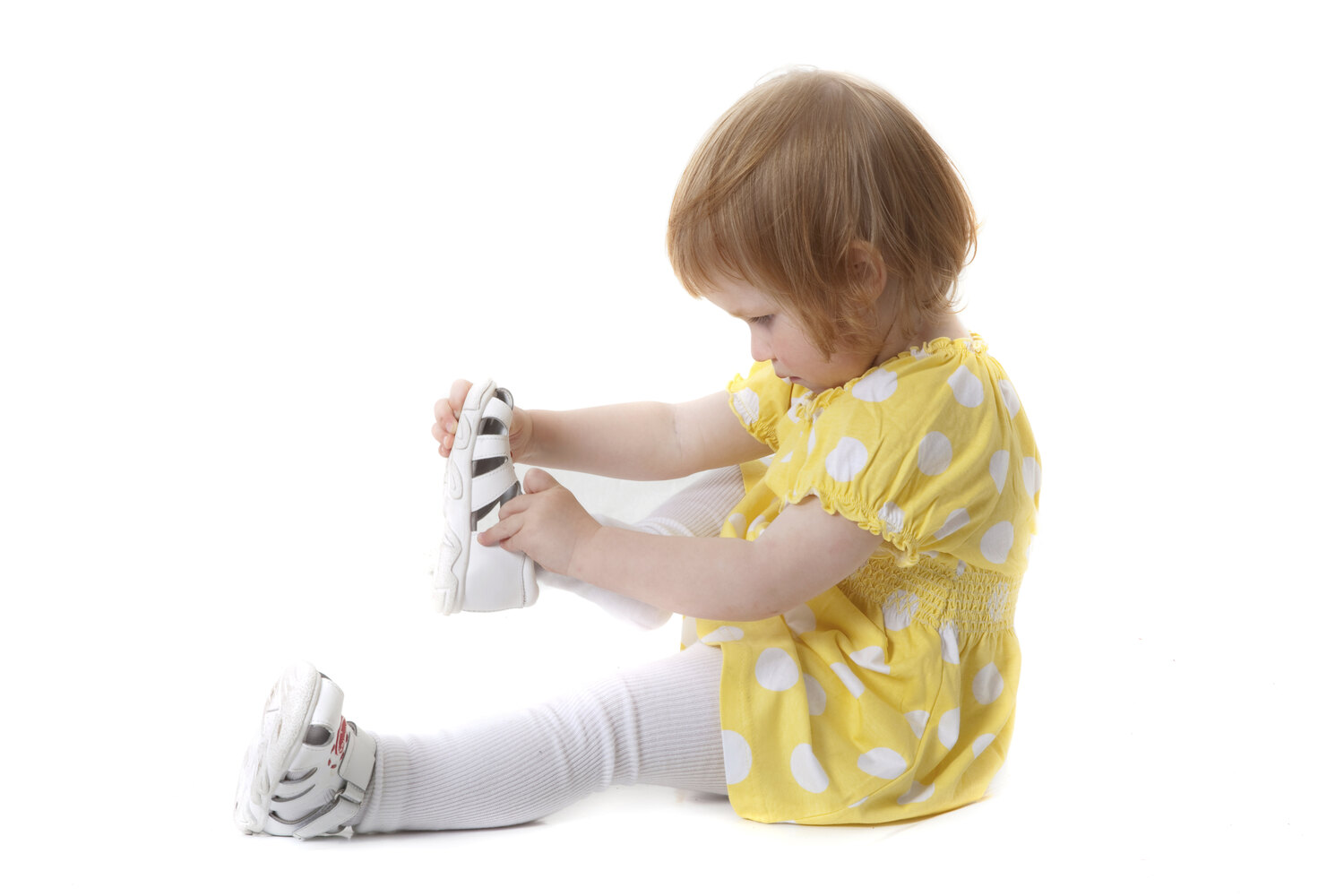 A little girl trying to put on shoes