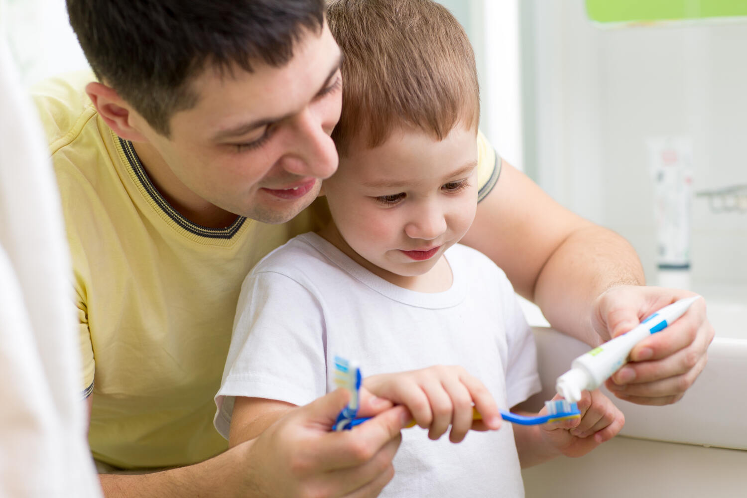 A toddler putting toothpaste on his brush