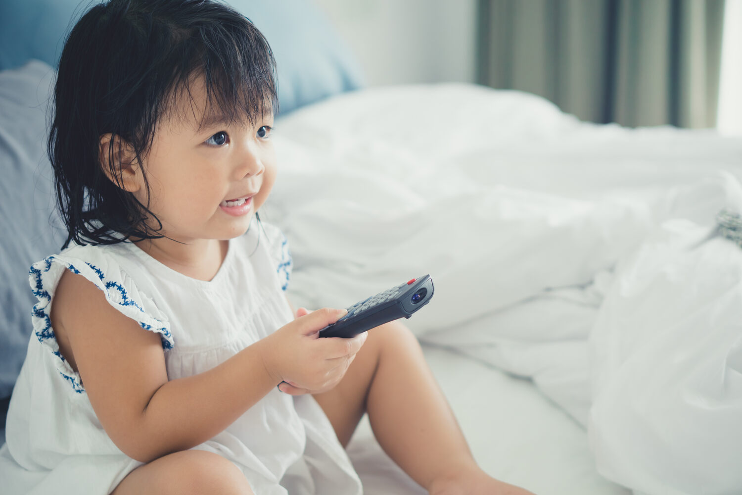 A toddler girl operating TV remote