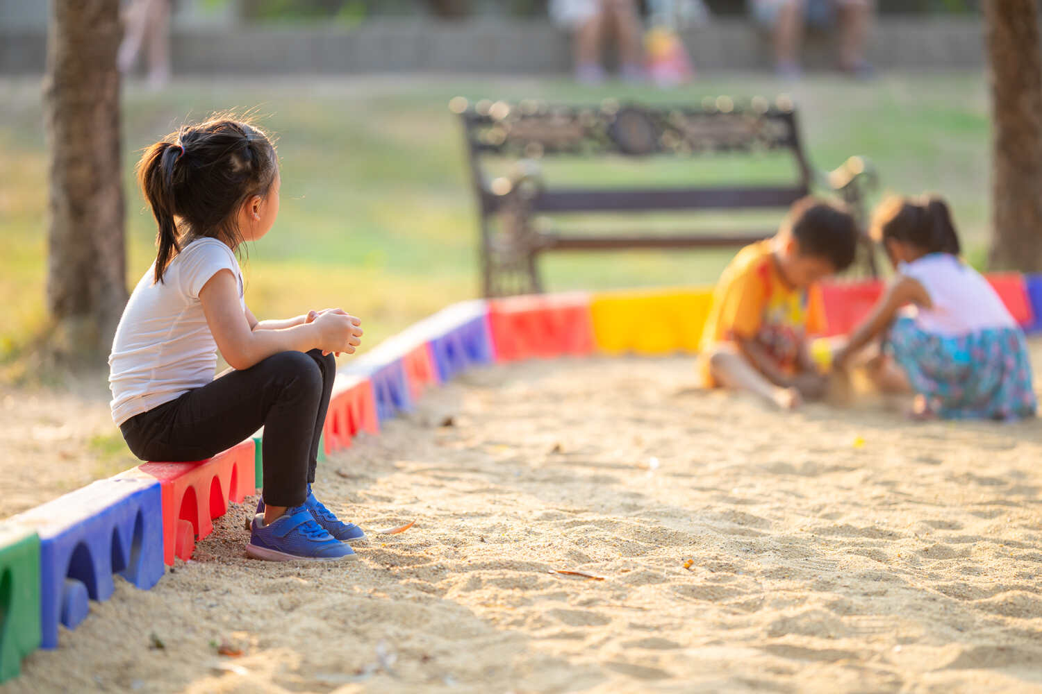 A little girl watching kids play