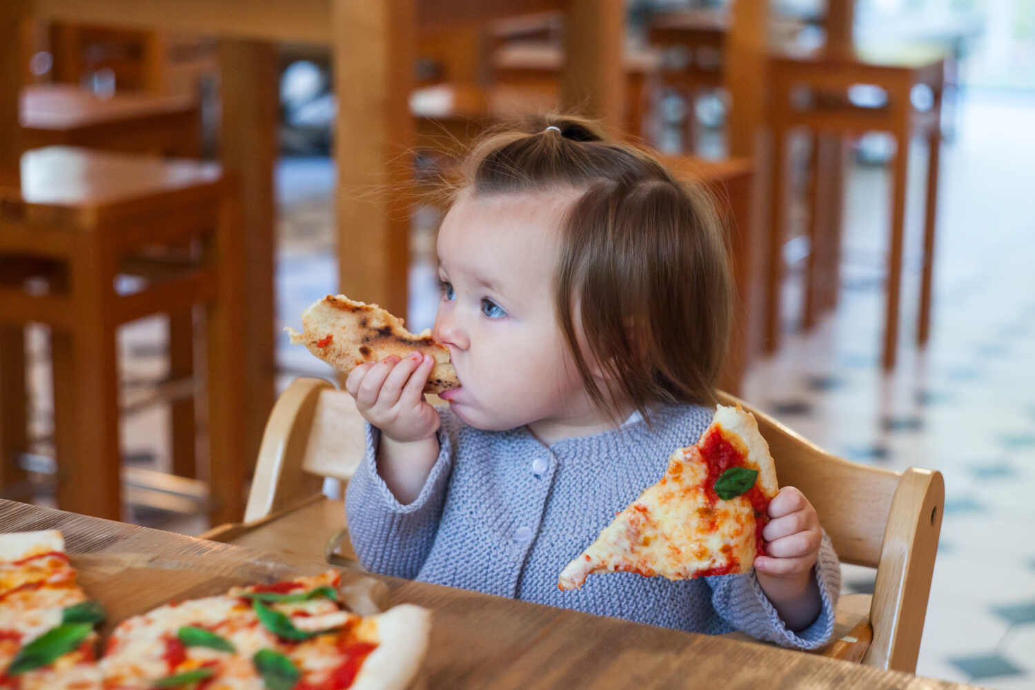 A toddler girl eating pizza