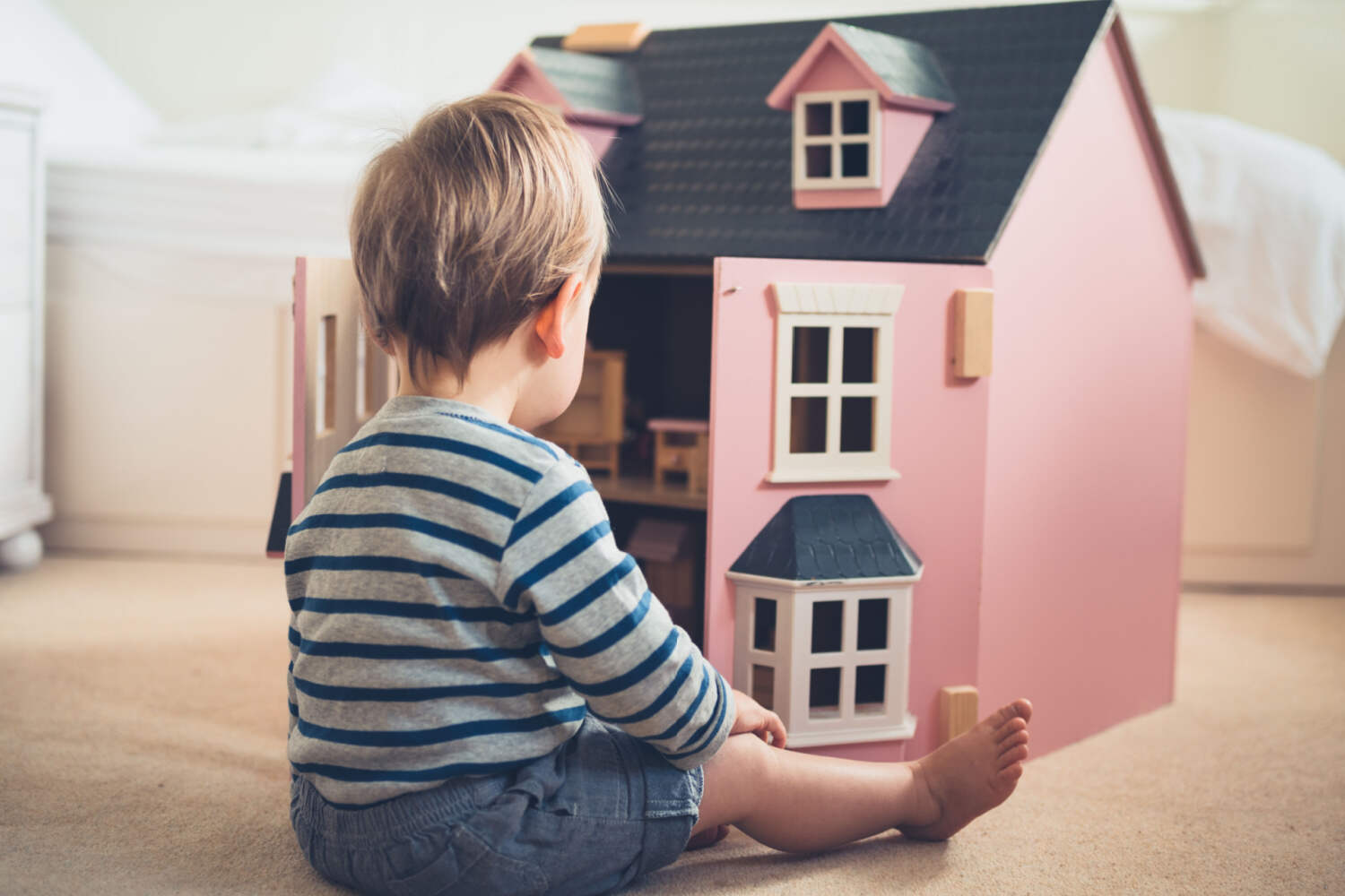 A toddler boy playing with doll house